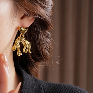 Detailed view of luxury gold leopard head earrings worn on model for vintage style