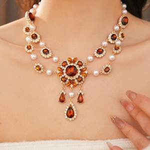 Detail der Vintage-Halskette mit braunem Edelstein, weißen Perlen und Gold-Anhängern