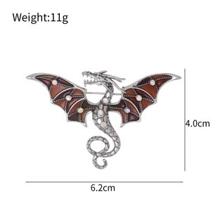Detail of red enamel dragon brooch showing 6.2cm width and 11g weight on white background