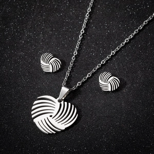 Silver stainless steel heart jewelry set with necklace and earrings on black background