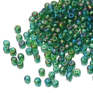 Close-up of 450g iridescent green glass seed beads scattered on a white background