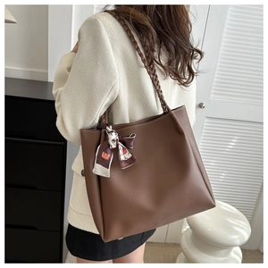 Détail du sac cabas en cuir marron foncé avec poignées tressées et foulard en soie imprimé