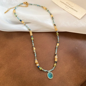 Detail of colorful beaded necklace with blue opal pendant and gold lobster clasp