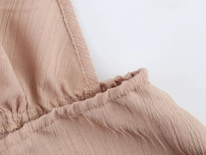 Vue macro du tissu texturé rose clair montrant les détails plissés et la qualité de couture