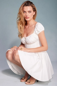 Détail de la robe blanche à manches bouffantes avec col carré et buste plissé élégant