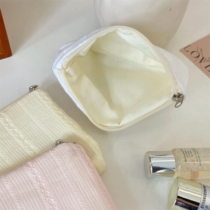 Detailed top view of textured knit cosmetic bags in white pink and yellow with silver zippers