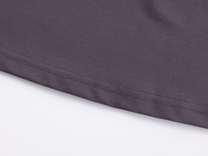 Detailed close-up of double-stitched hem and charcoal gray knit fabric on yoga top