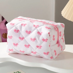 Vue détaillée de la trousse matelassée avec motifs de nœuds roses et fermeture éclair