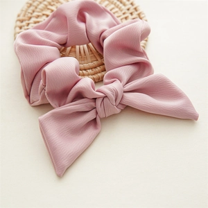 Detail of pink bow scrunchie with crinkled texture fabric on a decorative coaster
