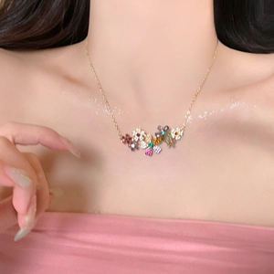 Gros plan d'un collier doré avec pendentifs fleurs en cristal coloré sur mannequin