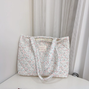 Détail du sac cabas matelassé à fleurs roses avec étiquette en tissu beige