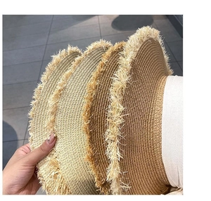 Detail of three stacked straw hats with elegant fringed edges and textured weaving