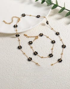 Detailed view of 18K gold titanium steel daisy necklace and bracelet set with natural stones