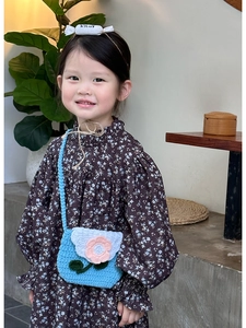 Detail of child wearing a floral dress with a blue crochet flower crossbody coin purse