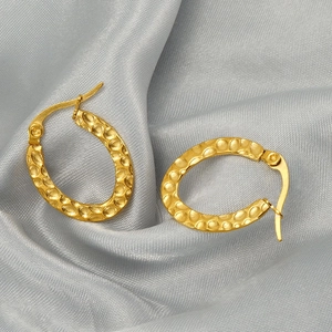 Classic gold stainless steel oval hoop earrings with hammered texture on silk fabric