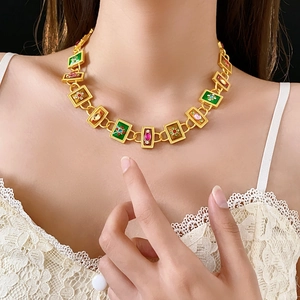 Detail view of vintage gold necklace with green and pink enamel flower links on model