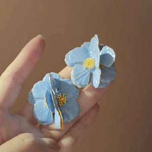 Macro view of blue enamel flower earrings with golden stamens and intricate petal details