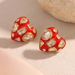 Detail of red enamel heart earrings with gold trim and zircons on natural stone