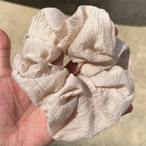 Beige French style oversized pleated hair scrunchie shown in high-quality outdoor detail