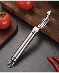 Stainless steel peeler on a wooden cutting board with fresh vegetables in kitchen setting