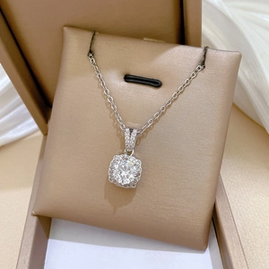 Detail of square zircon pendant with center round stone on a gold jewelry box