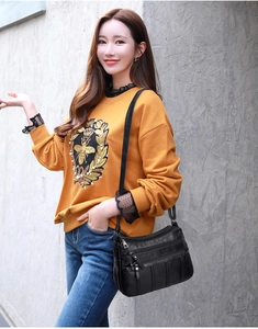Detail of a black multi-pocket crossbody bag with soft leather texture and zipper design