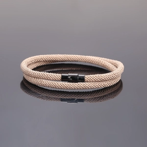 Woven double-layer rope bracelet with black magnetic clasp on a grey reflective surface
