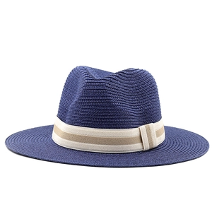 Detail of navy straw fedora hat featuring a beige striped ribbon band and bow decoration