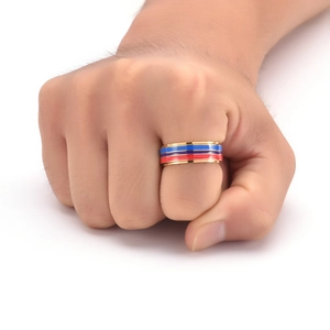 Close-up of a gold rotating ring with red and blue enamel stripes on a male model