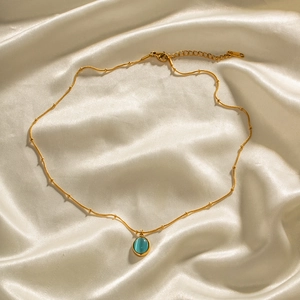 18K gold-plated stainless steel necklace with blue cat-eye stone on white silk background