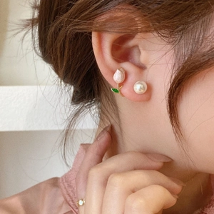 Detailed view of pink tulip flower and white pearl earring set on a model's ear