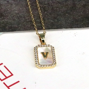Macro shot of 18K gold square shell pendant featuring a zircon-inlaid letter V necklace