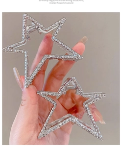 Detail of two silver Y2K star hair claws with sparkling rhinestones held by hand