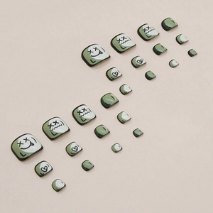 Avocado green and cream faux toenails featuring cute cartoon facial expressions