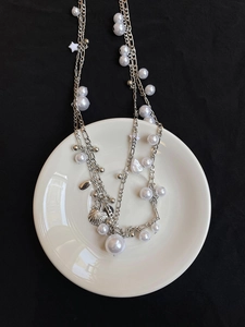 Detail of silver layered waist chain with pearls, shell pendant, and star charm