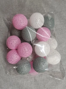 Detailed view of pink, white, and grey cotton ball LED string lights in clear packaging