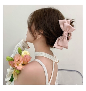 Detail view of a large pink satin bow hair claw clip styled on a half-up hairstyle