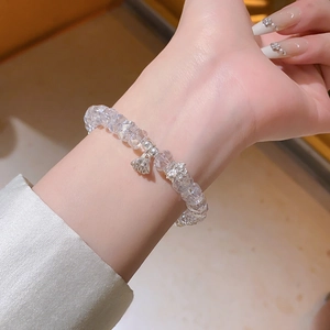 Détail d'un bracelet en perles de cristal facetté avec des breloques lotus sur le poignet