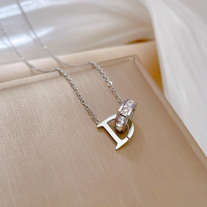 Close-up of silver steel necklace featuring D letter pendant and crystal-set ring detail