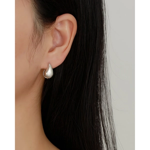 Close-up of a silver teardrop earring on model with high-polish metallic finish