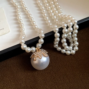Close-up of a large baroque pearl pendant with golden crown and sparkling rhinestones