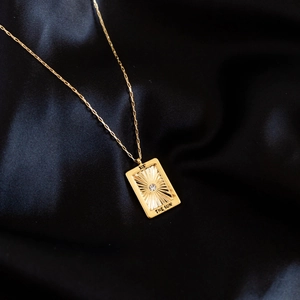 18K gold tarot pendant necklace featuring The Sun design on dark silk background