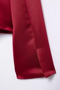 Close-up of deep red satin fabric texture on elegant Christmas two-piece skirt set