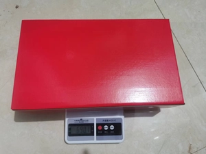 Medición de peso detallada que muestra la caja de regalo roja en una báscula a 690,7 g