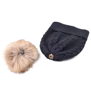 Primer plano del pompón de piel sintética desmontable del gorro de invierno de punto negro.