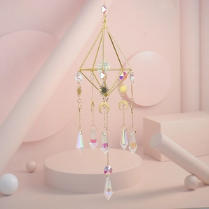 Detail of sun and moon metal charms with iridescent crystal prisms on a gold frame