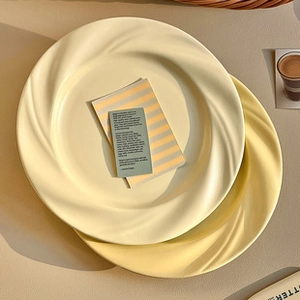 Detail of cream ceramic sauce dish with textured spiral rim and smooth matte finish
