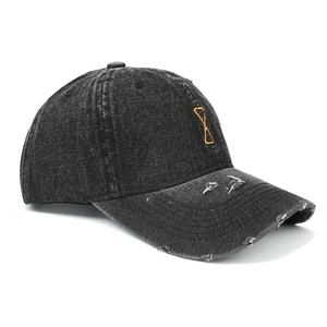 Close-up of distressed washed denim baseball cap with orange embroidery and frayed brim