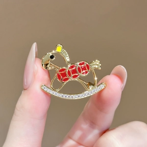 Golden rocking horse brooch with red accents and shimmering clear rhinestones inlay