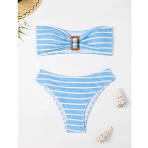 Flat lay of striped blue bikini with textured fabric, amber buckle, and beach decor